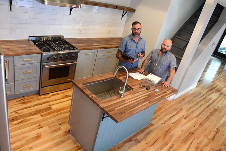 Acme Cabinet owners Keith Szczygiel and Sean Wrafter stand in the kitchen of a West Side home they gutted and refitted with their custom cabinetry. 
