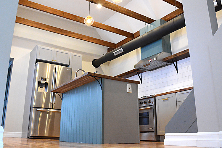 A custom kitchen, complete with island, oven hood, hardwood oak shelves, and hardwood counter tops.