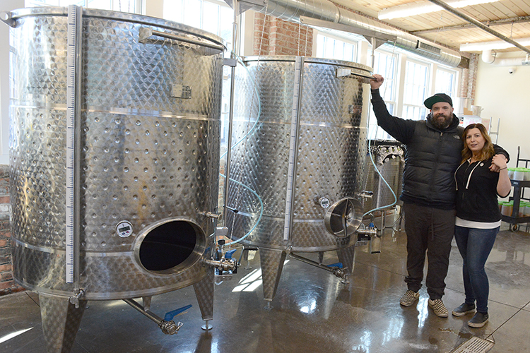 The Marvins stand near the large cooking vats in their facility. Barrel + Brine specializes in pickled and fermented foods.