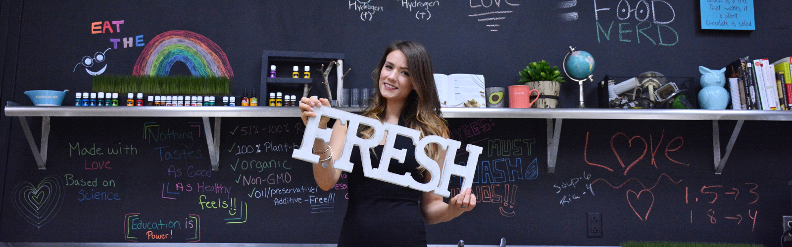 Sharon Cryan, founder and owner of Food Nerd, stands in front of her inspiration board holding an adjective that sums up her product.