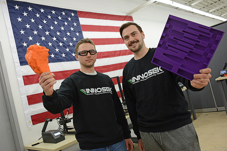 Innosek owners Brian Bischoff and John Kappel hold up a few of their 3D printed manufactured products at their 4090 Jeffery Blvd. facility. 