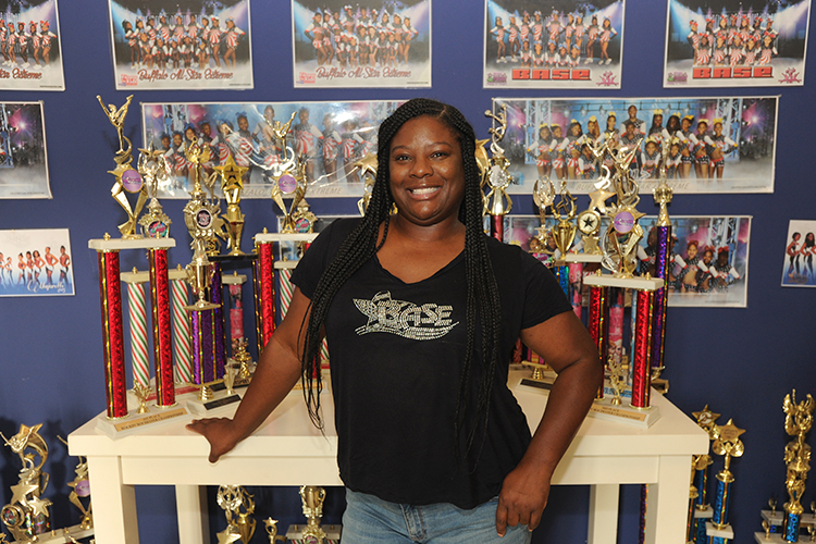 Ayanna Williams, founder and owner of Buffalo All-Star Extreme, 1245 Main St., Buffalo, stands in front of a wall of trophies and photos of the teams that won them. 