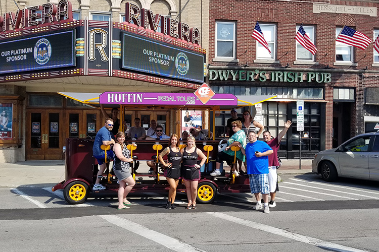 Happy peddlers stop on Webster Street in North Tonawanda in front of the Riviera Theatre, which is listed on the National and New York State Register of Historic Places, and Dwyer’s Irish Pub.