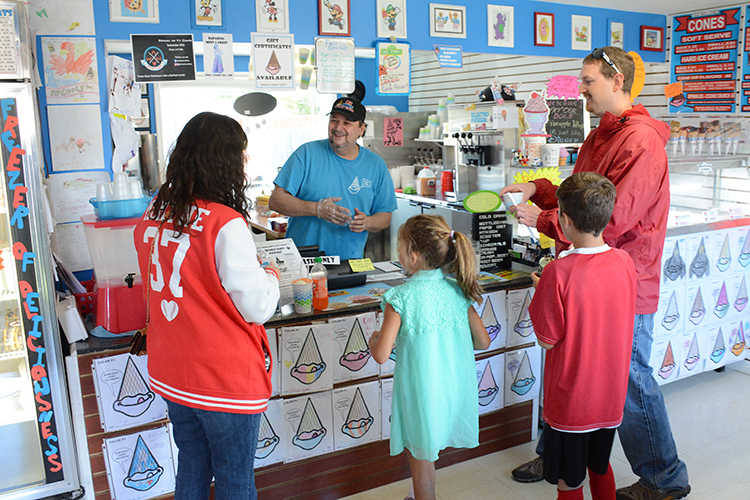 Joe Mancini assists a family hosting a birthday party at his ice cream shop.  