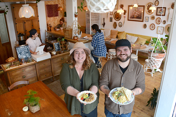 Root & Bloom owners Sarah and James Sendlbeck hold two of their dishes: the “Ruby,” house-cultured cashew yogurt with homemade granola and seasonal fruit with apple honey; and the “Nelson,” eggless scramble with house-cultured queso and local bread.