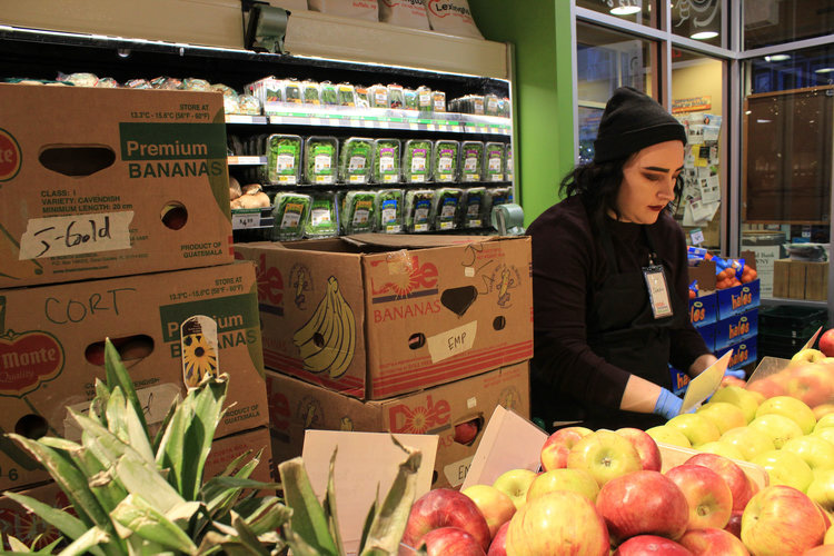 Sarah, an employee at the Lexington Co-op, organizes the organic apples.