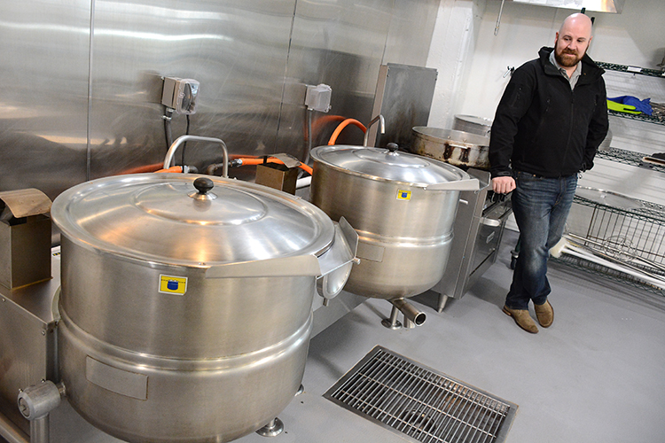 Zack Schneider, co-owner of Ru’s Pierogi, stands next to giant cooker vats at his Niagara Street restaurant and manufacturing facility.