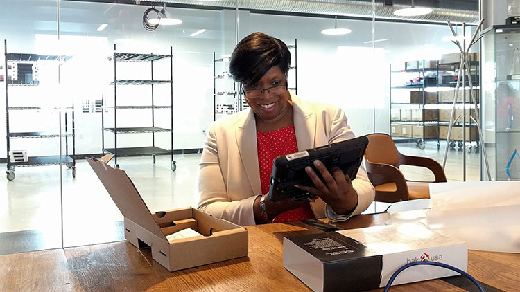 Sandra Ann Talley, winner of the UpstartNY sweepstakes, unboxing her new Bak USA Seal Tablet at Bak’s Buffalo headquarters.  Photo by LaunchNY.